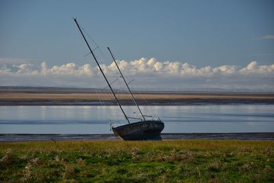 Sailboat moored on sea shore against sky