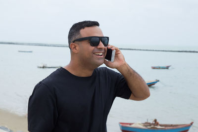 Young man using mobile phone in sea