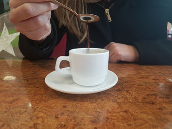 Close-up of hand holding coffee cup on table