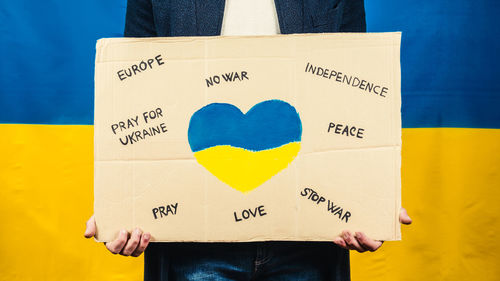 Boy holds cardboard with heart symbol for for the war in ukraine