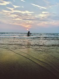 Silhouette man jumping on beach against sky during sunset