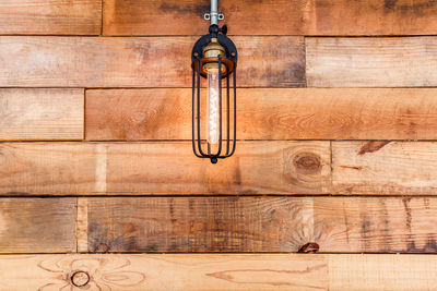 Close-up of electric lamp hanging on wooden wall