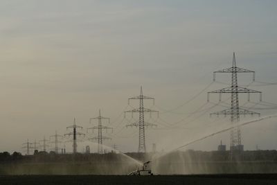 Electricity pylon on field against sky during sunset