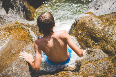 Rear view of shirtless man standing in river