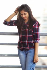 Beautiful young woman standing against railing