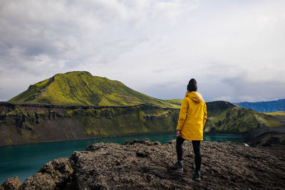 Rear view of man standing on mountain against sky