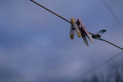 Low angle view of clothespins on clothesline against sky