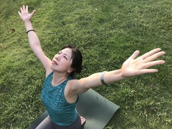 High angle view of woman with arms outstretched doing yoga on land