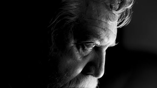 Close-up of man looking away against black background