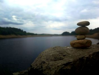 Stack of stones in lake against sky