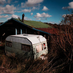 Hut and caravan on field against cloudy sky