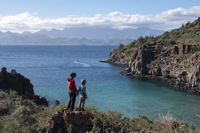 A woman and her son standing on a rock at a beach in del carmen island