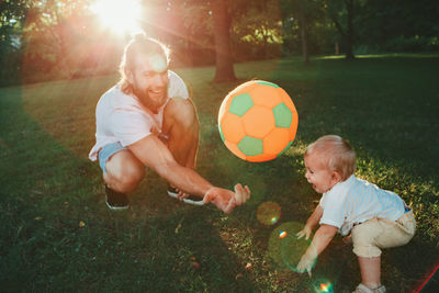 Siblings playing with ball in grass