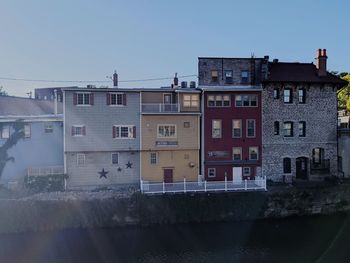 Residential buildings by river against clear sky