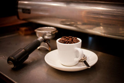 Close-up of roasted coffee beans in cup on table