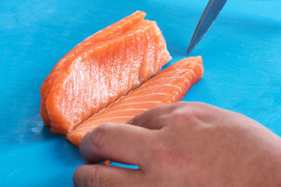 Cropped hand cutting fish on table