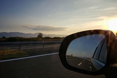 Close-up of side-view mirror against sky