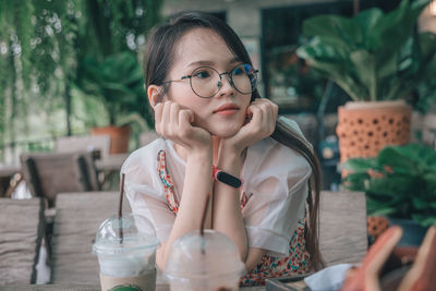 Portrait of woman wearing sunglasses sitting on table