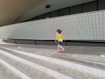 Full length of woman walking against wall