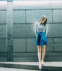 Full length of young woman standing against wall