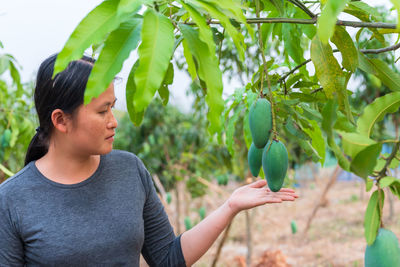 Midsection of man eating plant against trees