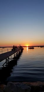 Silhouette pier over sea against sky during sunset