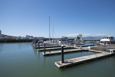 Boats moored at harbor against clear sky