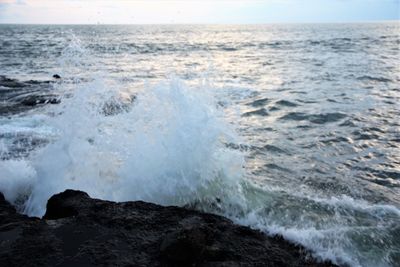 Waves splashing on shore against sky