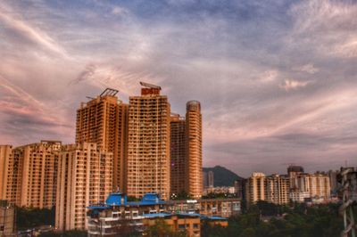 Modern buildings in city against sky during sunset