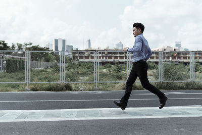 Side view of young man standing on road in city