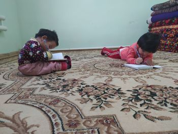 Rear view of women sitting on floor at home