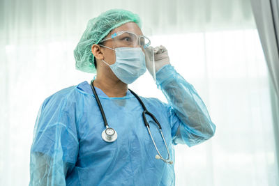 Portrait of doctor standing against wall