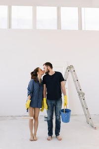 A young couple in love have moved into a new house and are making repairs painting white walls