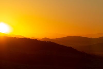 Scenic view of silhouette mountains against orange sky