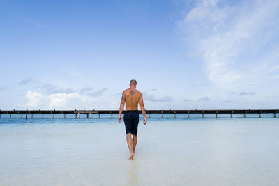 View from behind man standing in the water in maldives