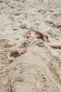 High angle view of girl buried in sand at beach
