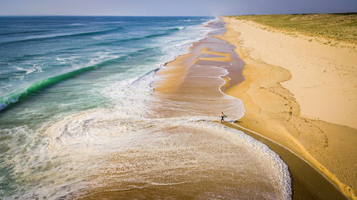 Aerial view of surfer walking towards shore