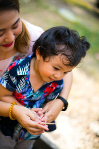 High angle view of mother with son holding incense while sitting outdoors