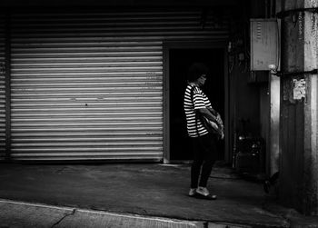 Full length of boy standing against shutter