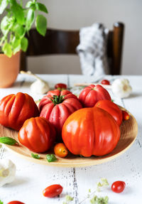 Tomatoes on the plate and white wooden background with basil plant garlic and chair
