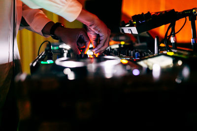 Dj is playing music. you can see his hands mixing music with his dj a party in the background.