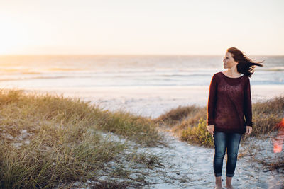 Woman walking on beach against clear sky