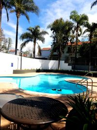 Palm trees by swimming pool against sky