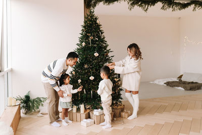 An asian multi-racial family with kids celebrate the christmas holiday in a decorated indoor house