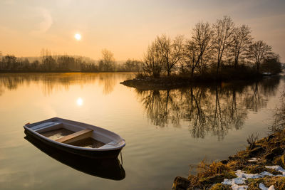 Boat in lake against sky during sunset