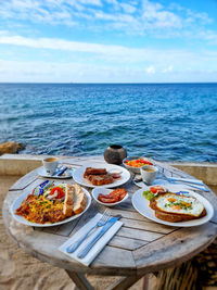 Food on table by sea against sky