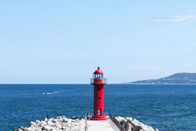 Lighthouse by sea against sky