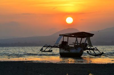 Silhouette boat in sea against sky during sunset