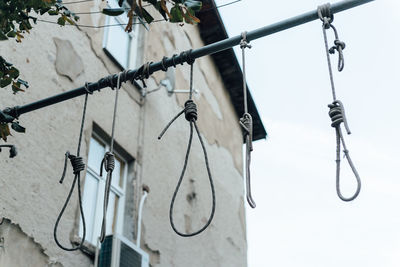 Low angle view of light bulbs hanging against sky