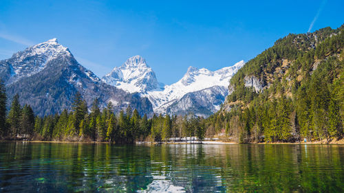 Snowcapped mountains behind a clear mountain lake.